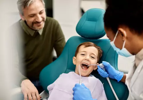 A child smiling and laughing as they have their mouth cleaned by a Pediatric Dentist in Peoria IL