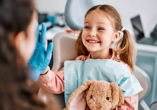 A happy little girl giving a high five to a Pediatric Dentist in East Peoria IL