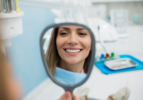 A woman smiles at her reflection during a dental visit. The Smile Center is a dentist's office in Peoria IL.