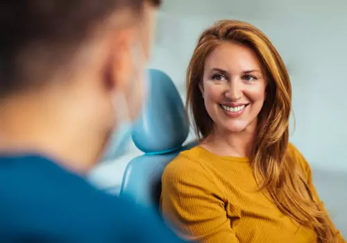 A woman is seen smiling at a dental appointment. The Smile Center offers dental crowns in Peoria IL.