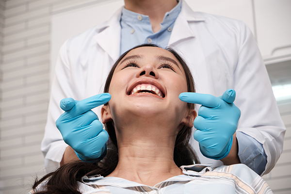 A woman smiles at the dentist’s office after getting emergency treatment